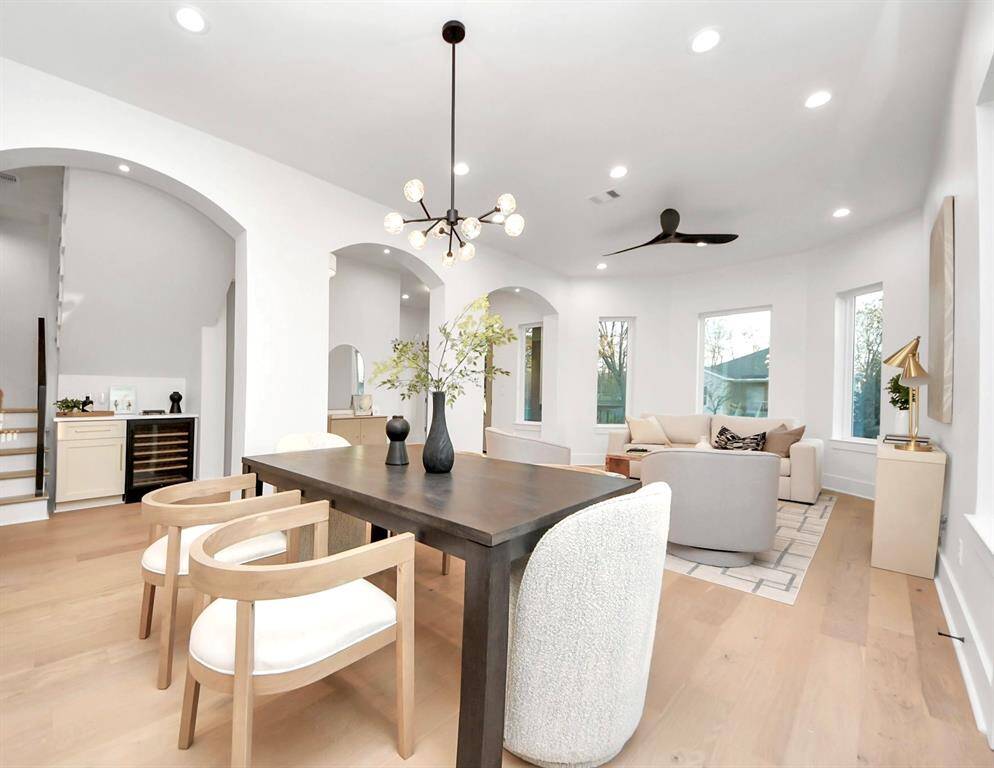 The dining room is highlighted by a black crystal chandelier overhead, adding an elegant touch, with a charming beverage area just through the archway.