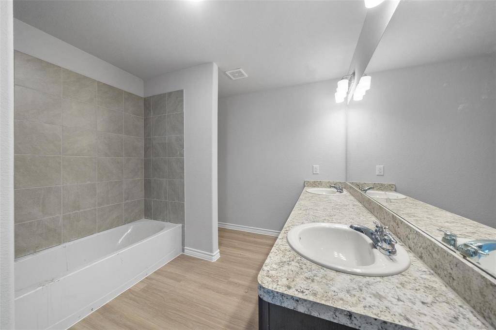 This bathroom offers ample counter space, abundant lighting, and a spacious shower/tub combo.