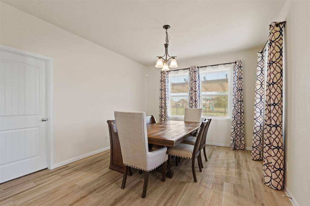This dining room is bright and open to the beautiful outdoor space and has a warm, inviting feel with neutral walls and wood-look flooring.