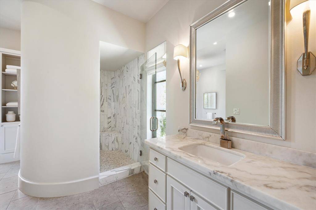 With its tasteful marble and natural stone accents, the en suite primary bathroom is reminiscent of a Roman bath.