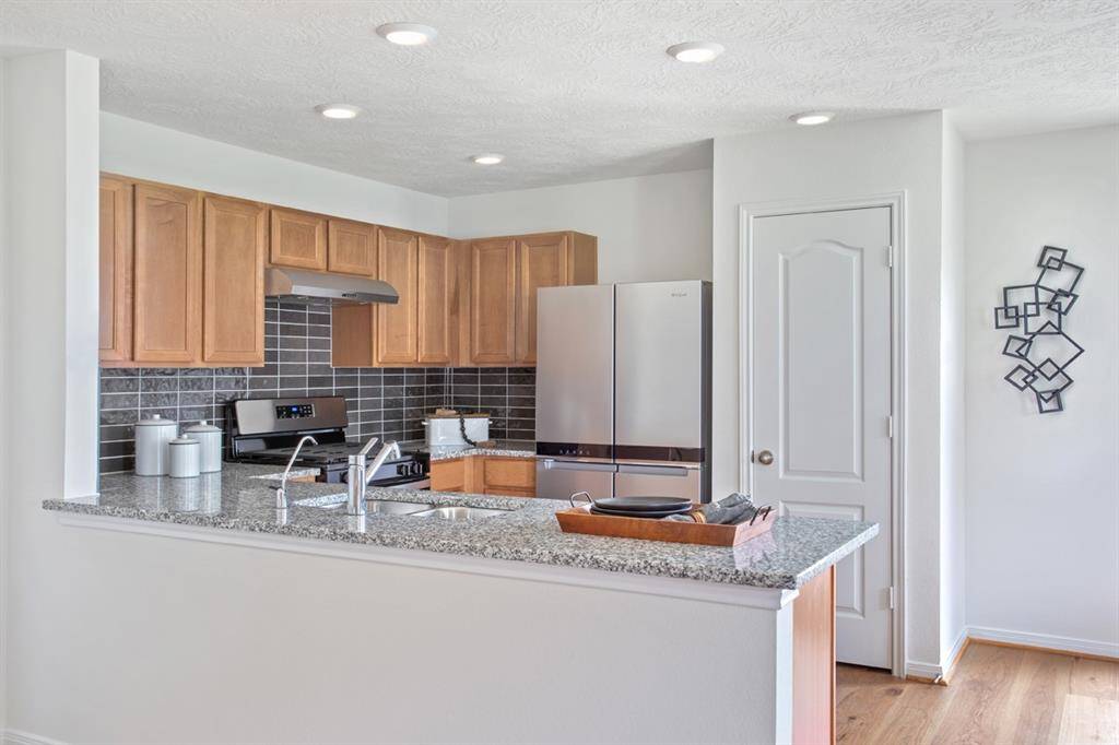 This kitchen will not disappoint! This gorgeous kitchen showcases high ceiling, recessed lighting, engineered wood flooring, stained wood cabinets, SS appliances, granite countertops, beautiful tile backsplash, and a pantry!