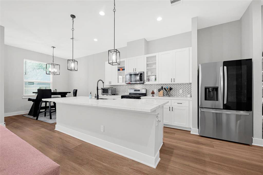 Kitchen w/ quartz island and designer backsplash. Refrigerator stays