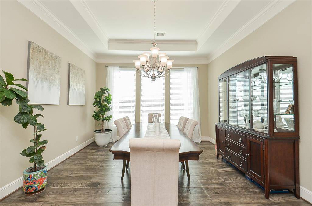 Simplicity in streamlined walls and intimate tray ceiling bring a quiet elegance to the formal dining space, bathed in natural sunlight by triple floor-to-ceiling windows.