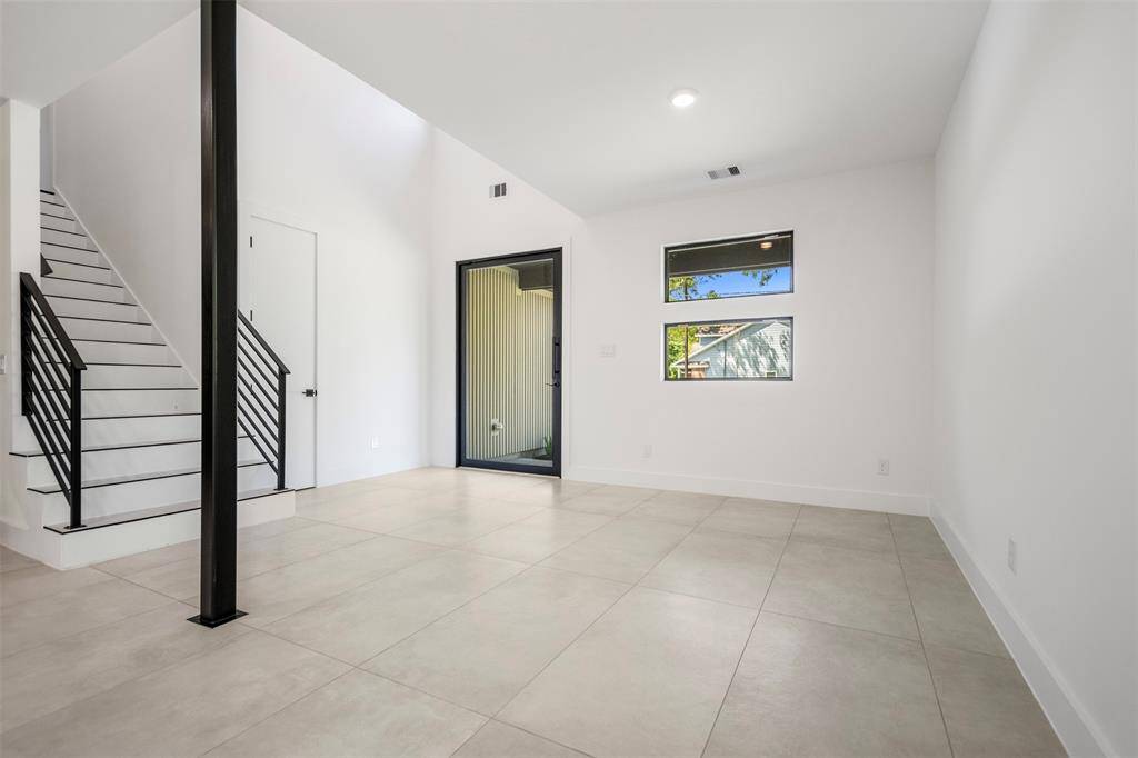Step through the custom pivot front door into a bright, airy foyer featuring a sleek modern staircase, convenient coat closet, and a versatile flex space off to the side.