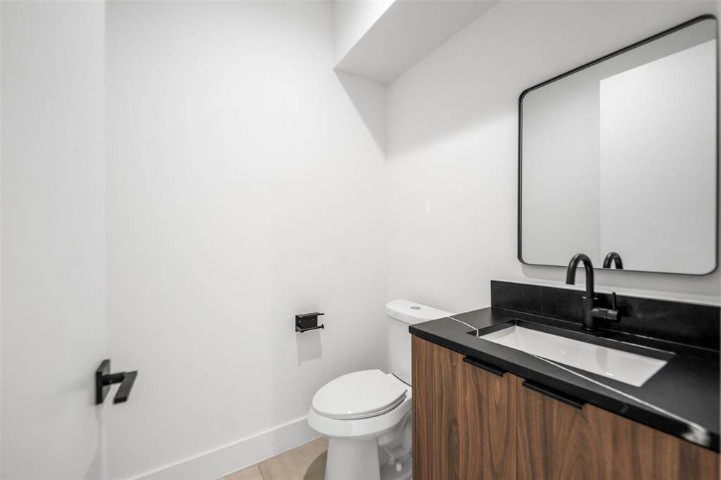 Refined and minimalist powder bath showcasing a striking black quartz countertop, sleek clean-lined mirror, and contemporary vanity