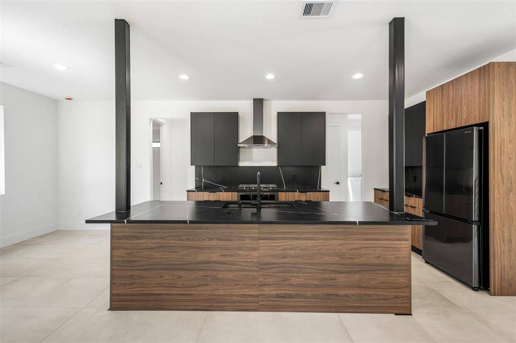 Bold and modern kitchen featuring black quartz countertops with seating, matte black cabinetry, and warm wood finishes for a striking contrast.