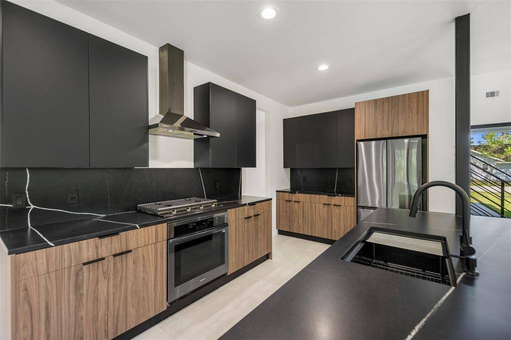 Sleek and functional layout with premium appliances, vent hood, and striking slab backsplash detail.