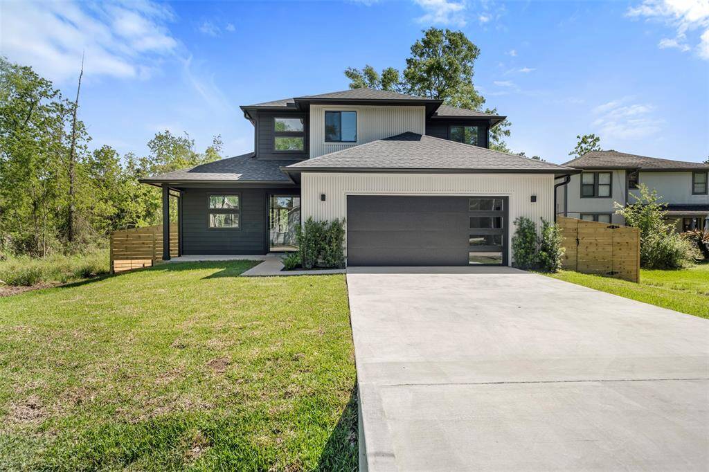 Contemporary curb appeal meets functionality with a sleek black garage door, vertical siding accents, and a wide concrete driveway.
