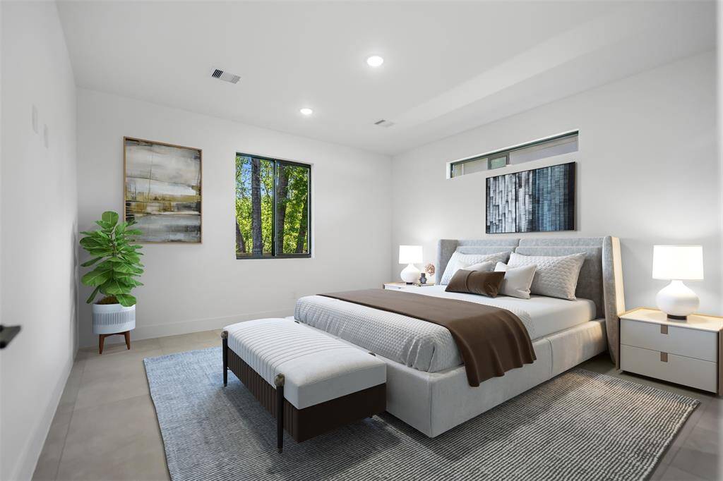 Staged primary suite exuding warmth and tranquility, complete with a cozy king-size bed, tray ceiling, recessed lighting, and large picture windows overlooking lush greenery.