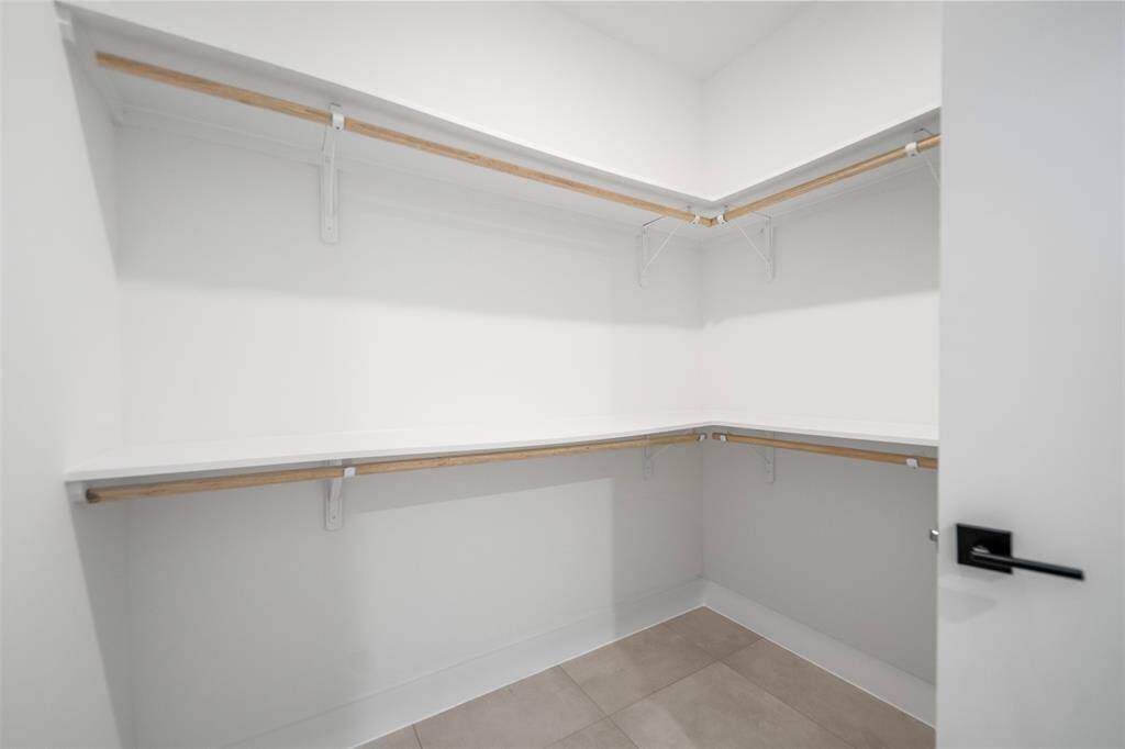 Walk-in primary closet offering ample storage with wraparound shelving and double hanging rods—ready to be customized to fit your wardrobe needs