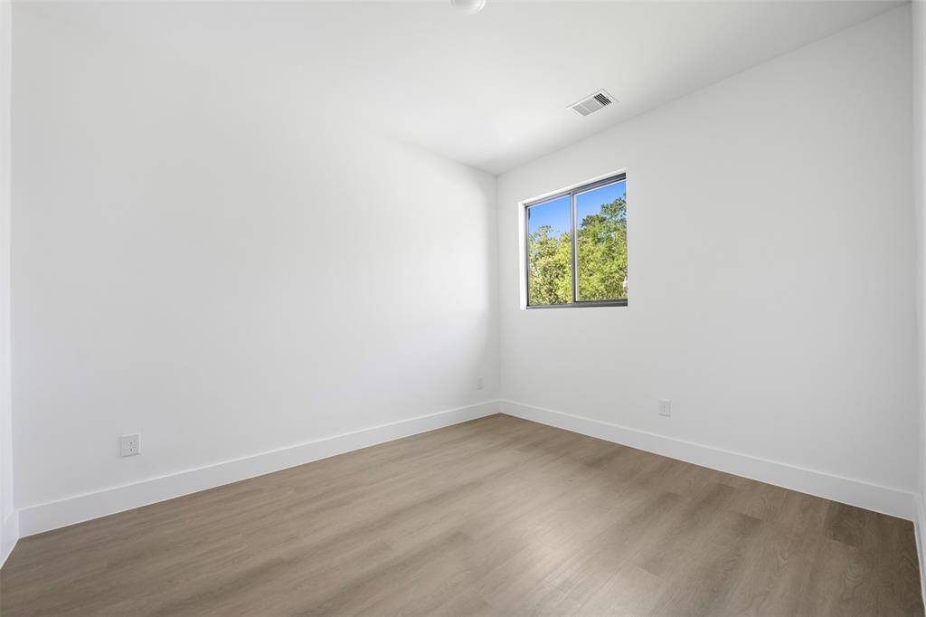 Bright third bedroom featuring corner views, wood-style flooring, and a minimalist modern design ideal for a cozy retreat or creative space.