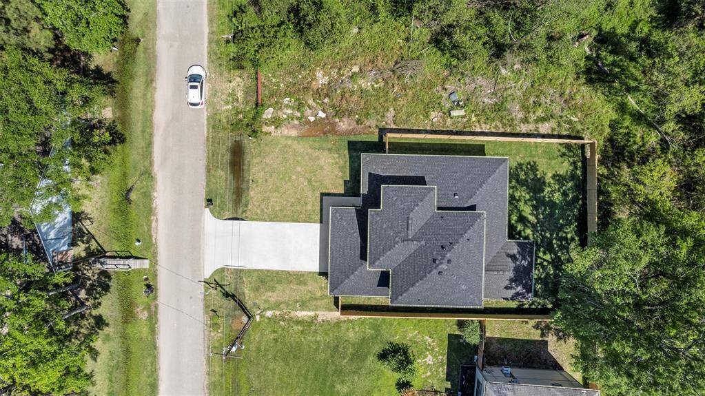 Aerial view of the property showing the home’s footprint, long driveway, and surrounding greenery without side or back neighbors, highlighting its placement on a spacious lot.