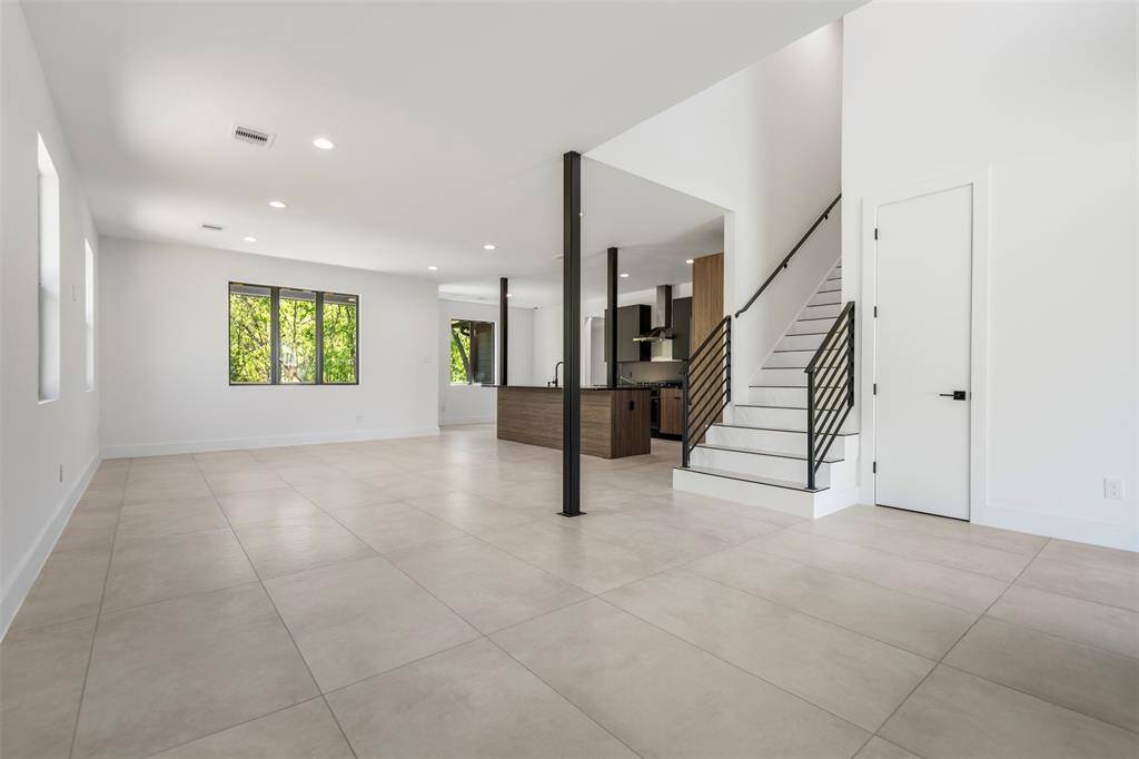 Open-concept living with oversized tile flooring, modern black accents, and a seamless flow into the designer kitchen.