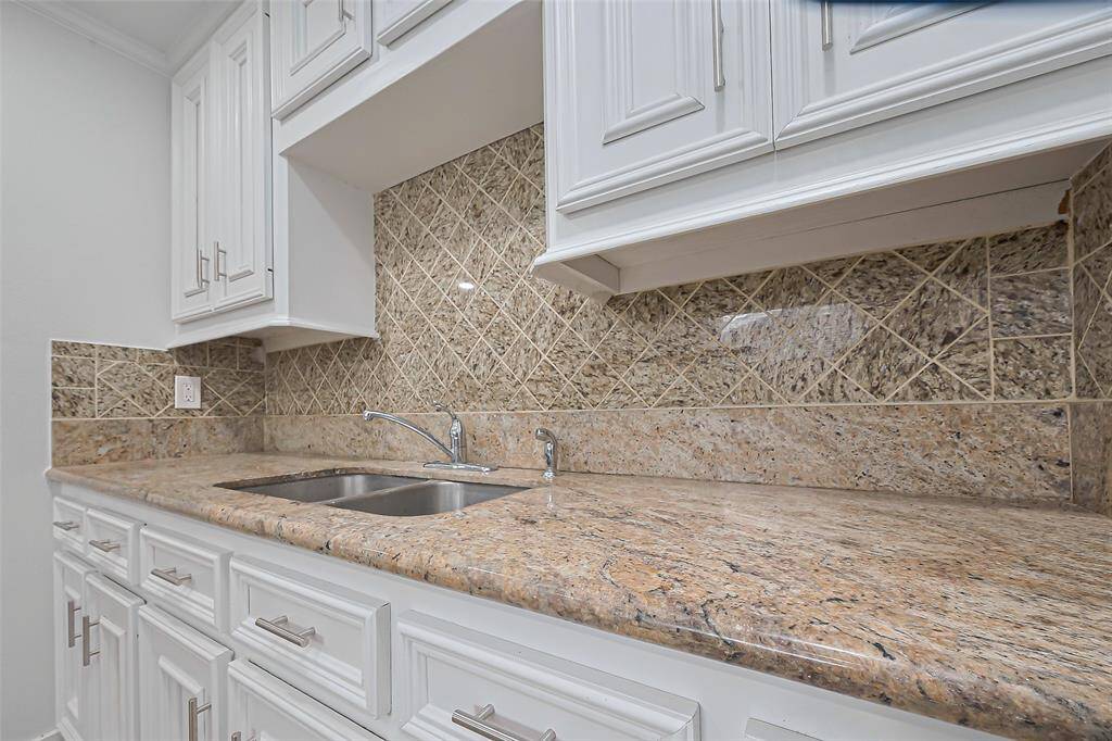 The kitchen features a double sink, set on an expansive countertop that matches the backsplash perfectly.