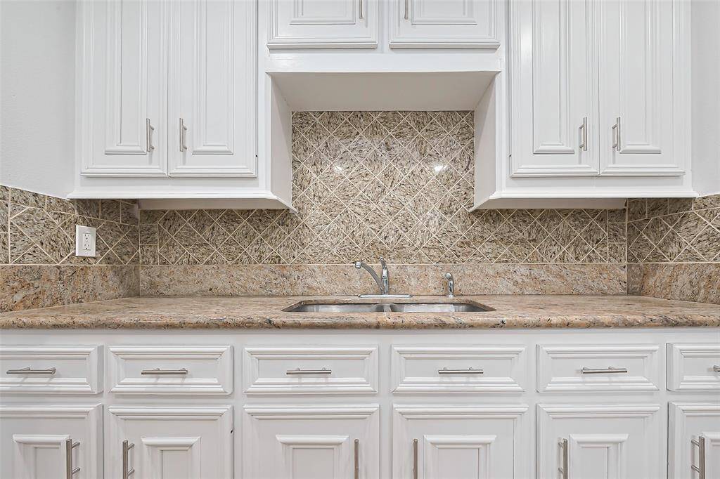 The textured backsplash in the kitchen adds a sophisticated touch, offering a stylish contrast against the white cabinetry.
