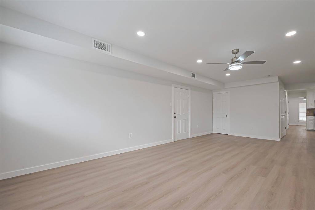 This formal dining room is dressed in a cool neutral palette, complemented by warm laminate flooring, offering a versatile space for various styles.