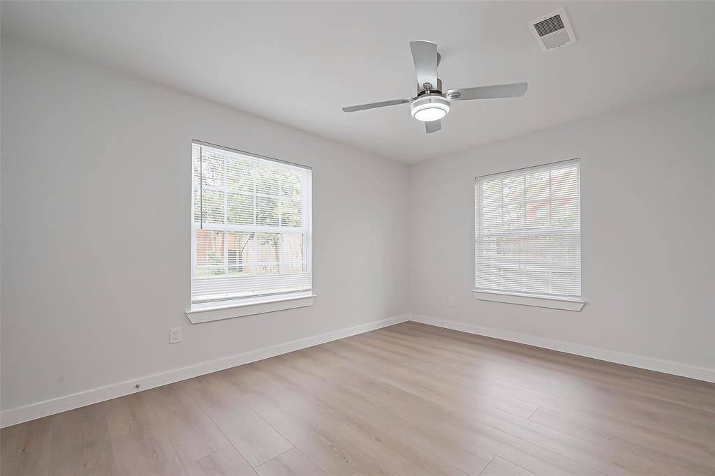 The primary bedroom is spacious and serene, featuring oversized windows and a ceiling fan, ensuring plenty of light and airflow throughout.