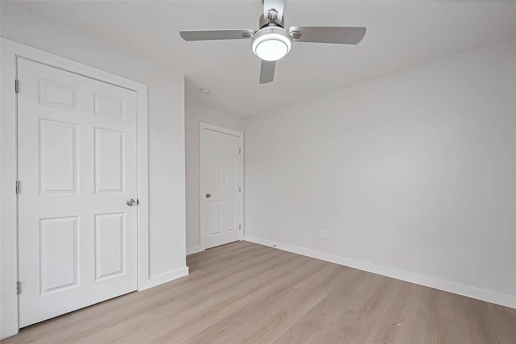 This bedroom features the same warm laminate flooring as the rest of the home, paired with light-colored walls that create a calm and restful ambiance.