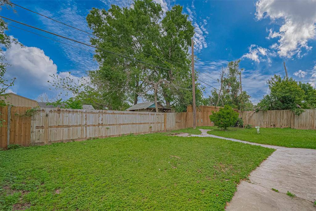 The backyard offers wide stretches of lush, green grass within the fenced area, providing plenty of room for play, gardening, or simply enjoying the outdoors.