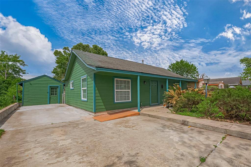 A charming exterior featuring a green hue that beautifully complements the lush greenery and vibrant plants along the front, adding curb appeal and welcoming warmth.