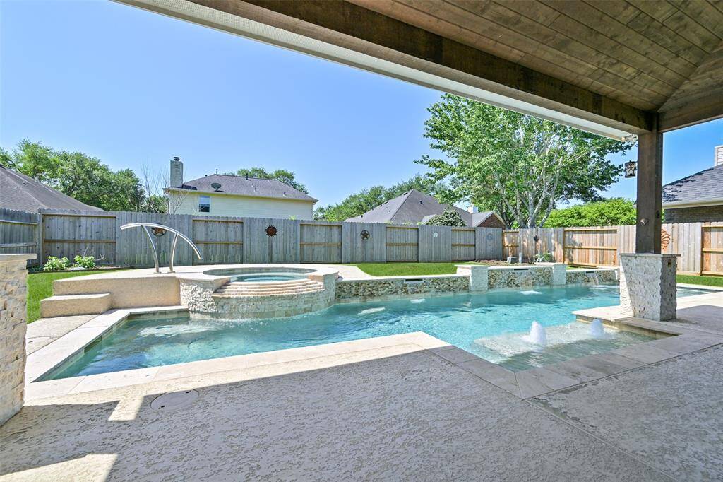 LUXURY MEETS LEISURE IN THIS STUNNING BACKYARD WITH A WRAPAROUND POOL AND BUBBLING SPA.