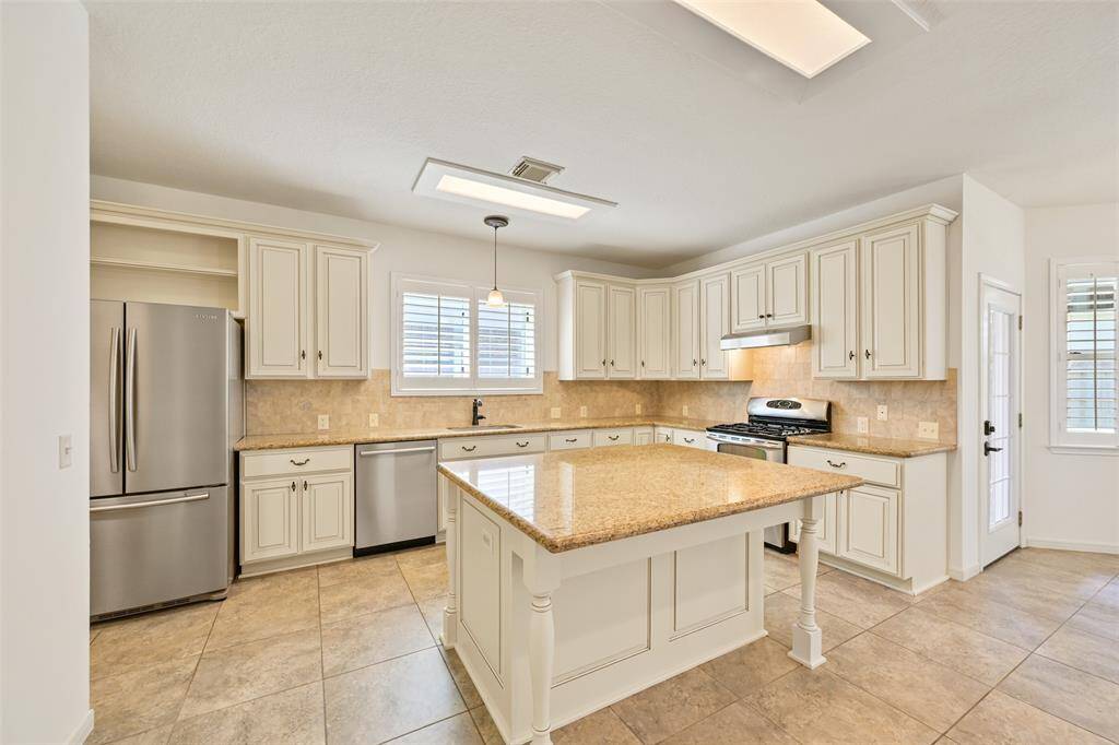 HAMRE-REMODELED KITCHEN WITH BENEDETTINI CABINET FRONTS, PULLOUT DRAWERS, GRANITE COUNTERS, AND A MODERN COUNTRY ISLAND—PERFECTLY COMPLEMENTED BY ITALIAN TILE FLOORING AND A 2021 BOSCH DISHWASHER.