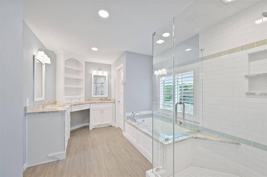 FULLY REMODELED PRIMARY BATHROOM WITH A MODERN TUB, AND A GLASS ENCLOSED WALK-IN SHOWER.