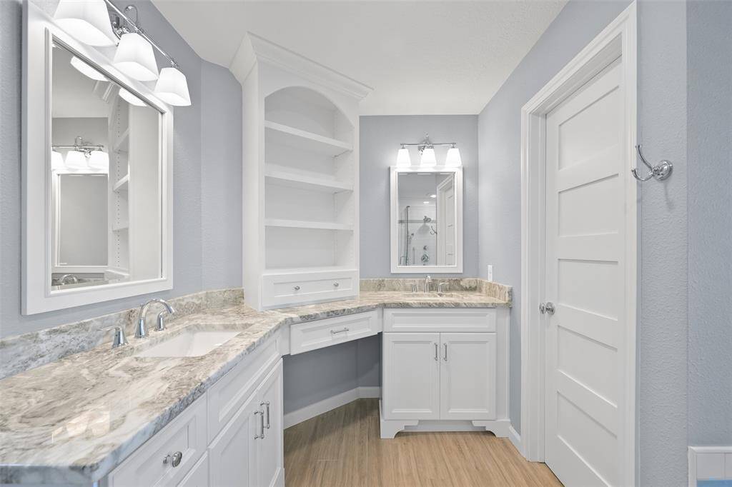 PRIMARY BATHROOM REMODEL FEATURING NEW CUSTOM CABINETS, GRANITE COUNTERTOPS, MODERN LIGHTING, AND A BUILT-IN VANITY.