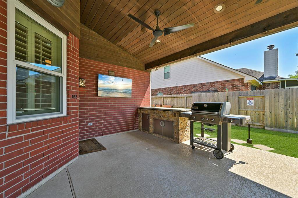 ENJOY YEAR-ROUND ENTERTAINING UNDER THIS COVERED PATIO WITH A WOOD-STAINED CEILING AND BUILT-IN BAR & GRILL AREA.