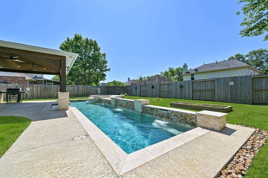 COOL OFF IN STYLE WITH THIS CUSTOM POOL AND SPA COMBO, SURROUNDED BY STONE ACCENTS AND A FULLY FENCED YARD FOR PRIVACY.