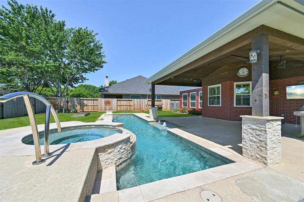 RESORT-STYLE BACKYARD WITH A SPARKLING POOL AND SPA , AN EXTENDED COVERED PATIO AND AN OUTDOOR BAR.
