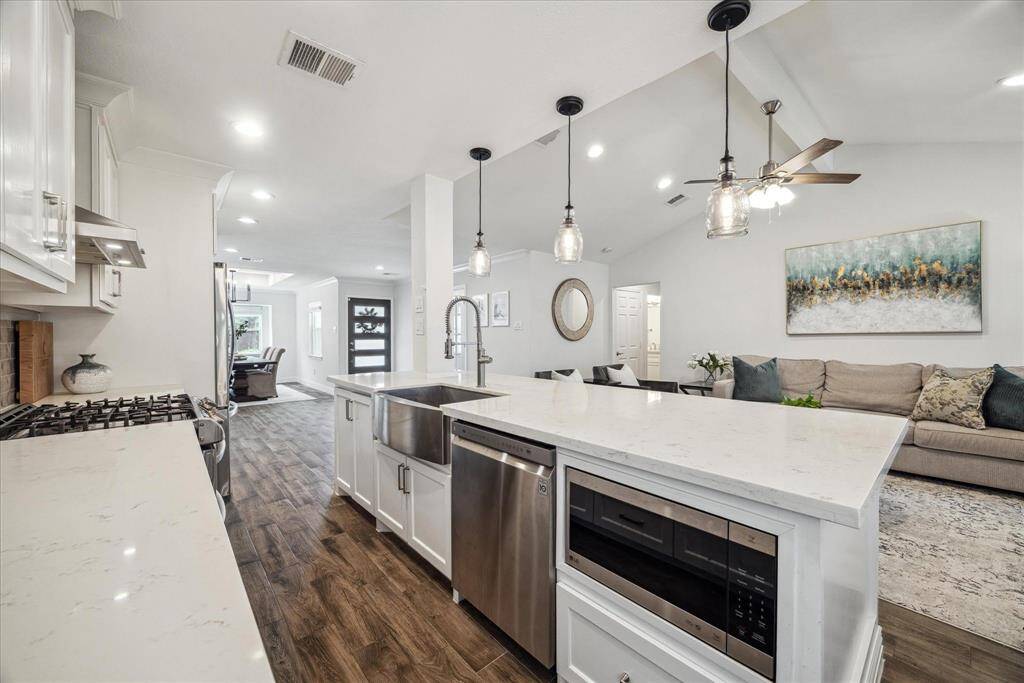 The island has additional storage and a convenient, built-in microwave. The openness of the kitchen, recessed lighting, and plentiful windows create a light and bright living area.