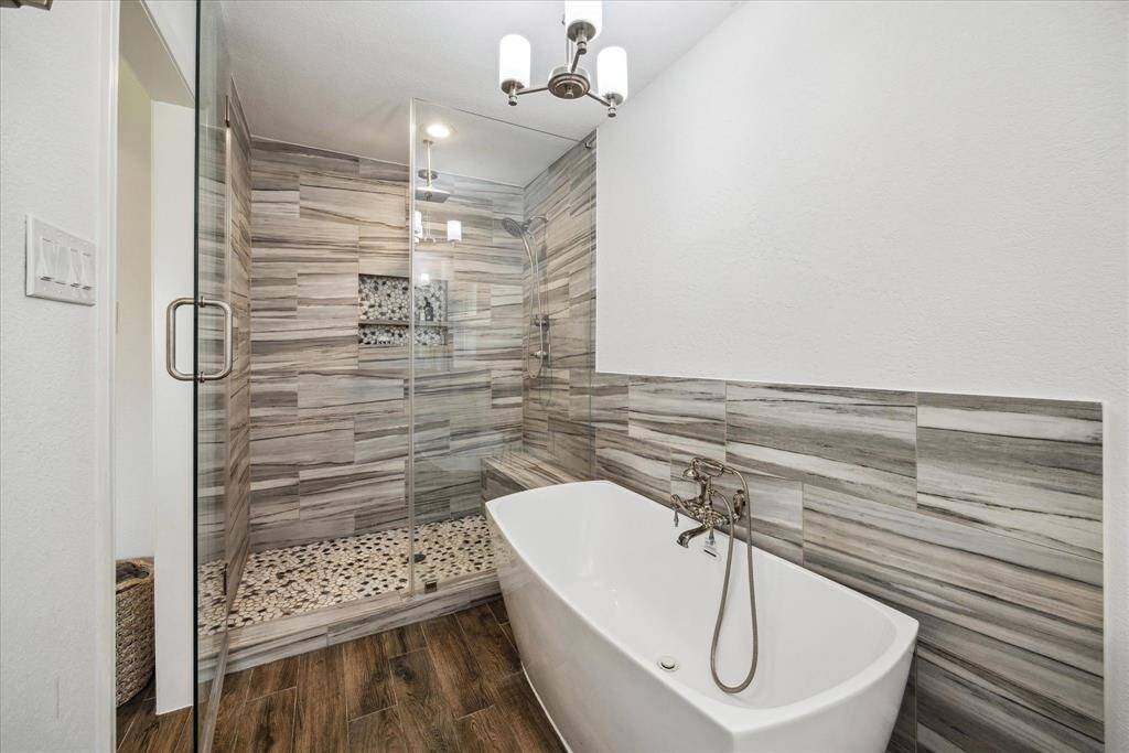 Enjoy both a large soaking tub and a shower with a niche, waterfall shower head, and frameless glass door.