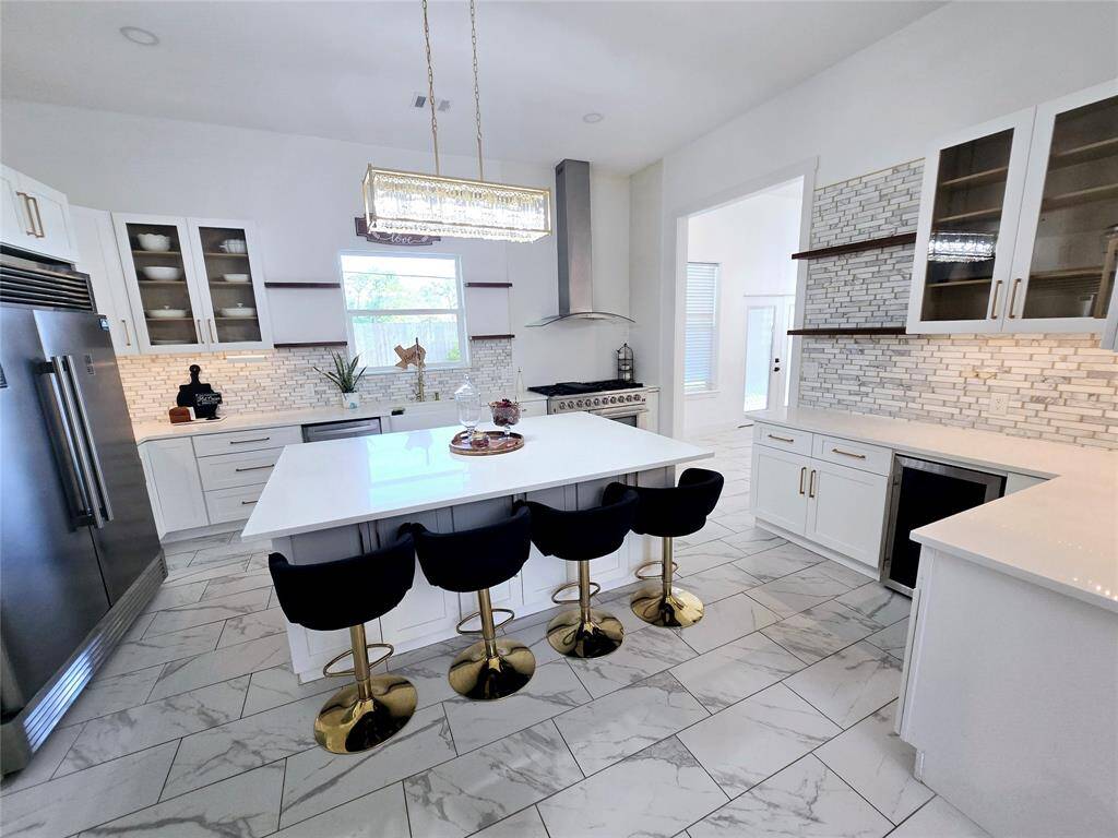 This modern kitchen features a stainless steel refrigerator, wine chiller, double ovens, and spacious island that seats 4.