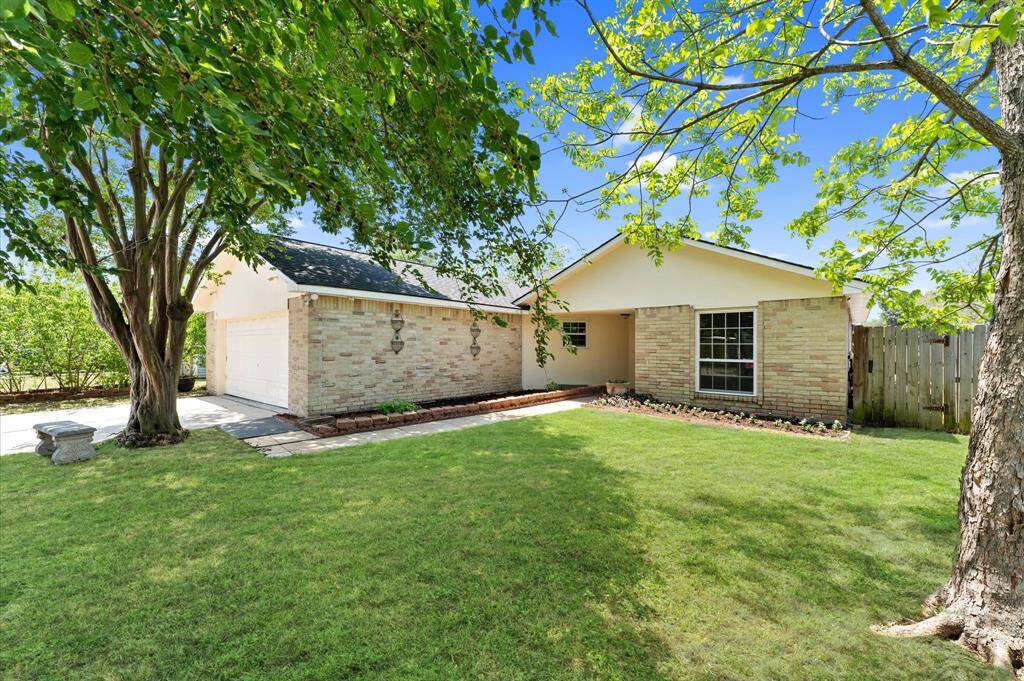 Charming front view showcasing the home's inviting entrance, lush lawn, and mature trees for added privacy and curb appeal.