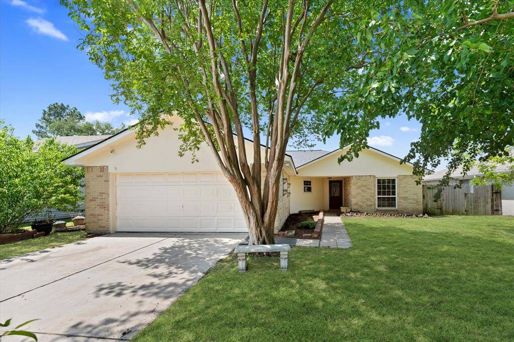 Charming front view of a cozy, single-story home with a welcoming entrance, spacious garage, and lush green lawn framed by mature trees.