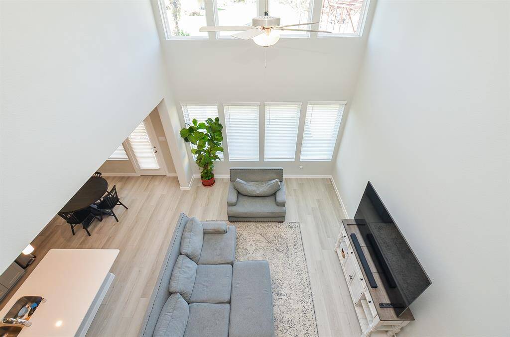This bright, airy living space features a high ceiling with large windows that let in natural light.  The neutral tones and modern design create a welcoming atmosphere.