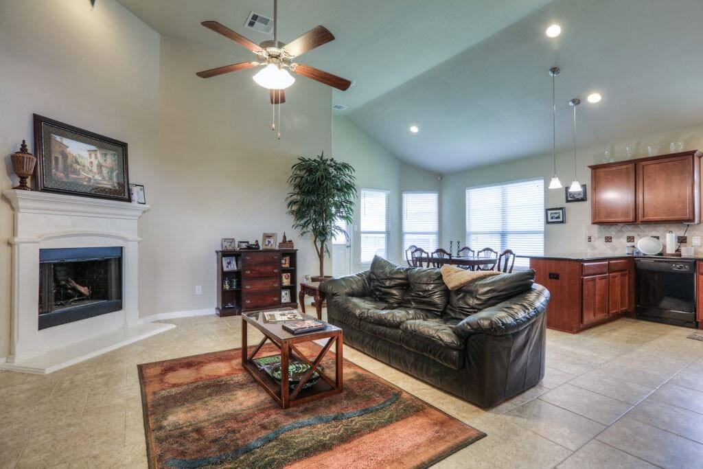 Corner fireplace & vaulted ceiling with recessed lights and ceiling fan in the living area of the open concept home.