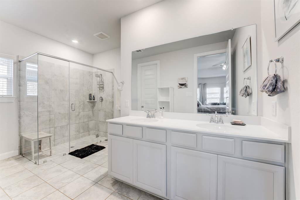 Primary bathroom has tile flooring, double sinks, and an oversized walk in shower.