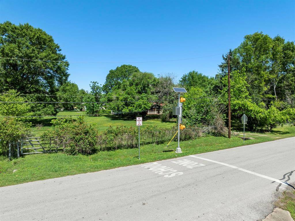 Positioned across from a designated school zone, the lot sits in a developed area with utility access and surrounding residential structures.