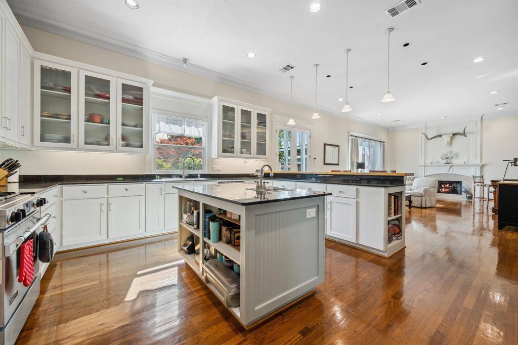 The kitchen offers scenic views of the backyard oasis and includes built-ins for added storage, along with elegant glass-front cabinetry.