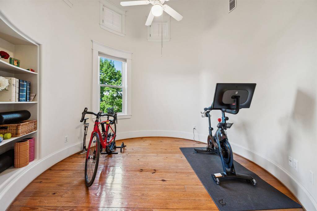Currently used as a home gym, this versatile room can easily serve as a home office, game room, or workout space. Featuring hardwood floors, a ceiling fan, and a window for natural light, it also includes built-in shelving for extra storage and plenty of room for fitness equipment.
