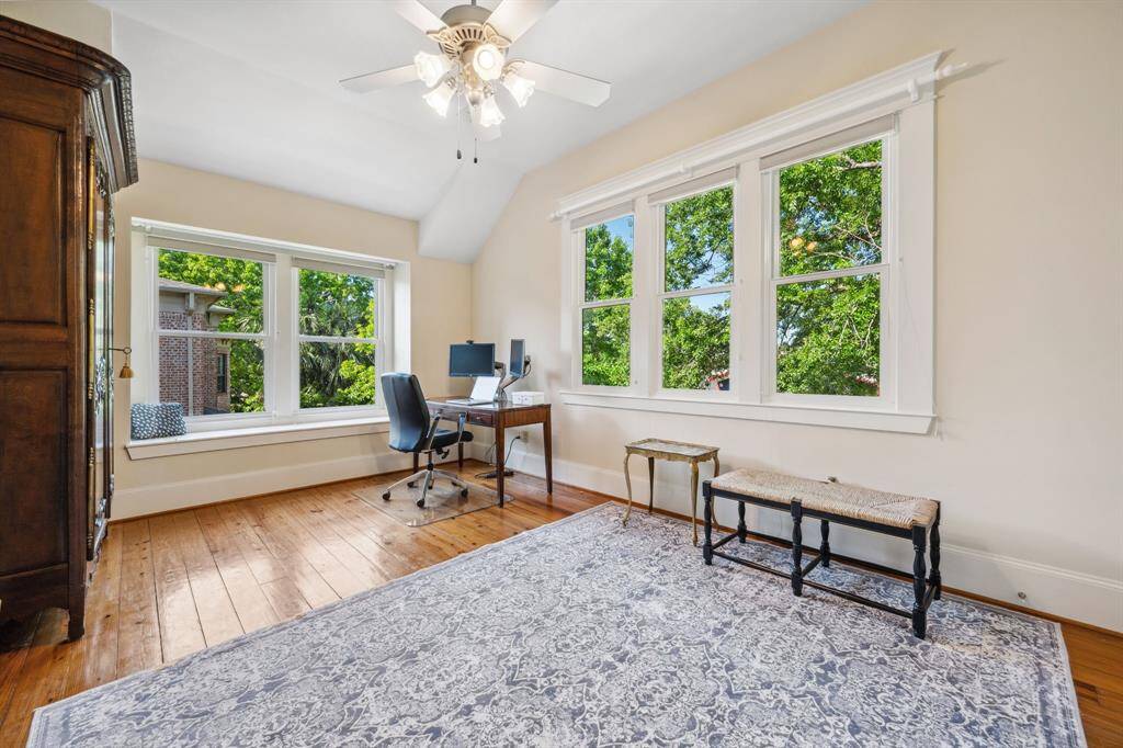 Secondary bedroom offering tree-top views, hardwood floors, and a charming window bench—perfect for reading or relaxing.