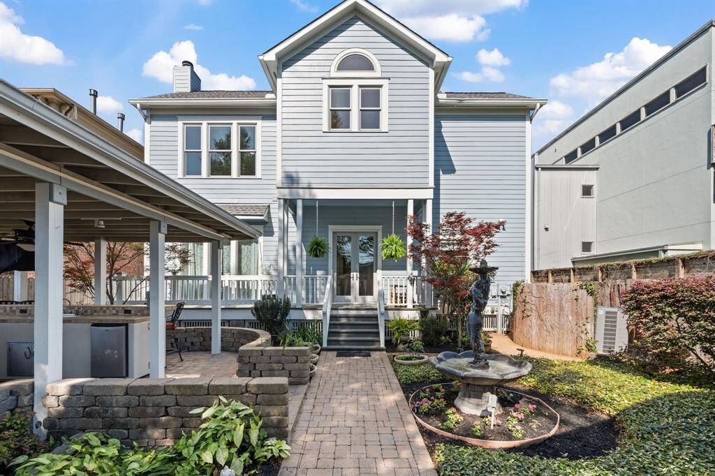 The backyard features a paved patio with a covered outdoor kitchen area, complemented by a decorative fountain that enhances the tranquil ambiance. An ideal space for both entertaining and relaxing.