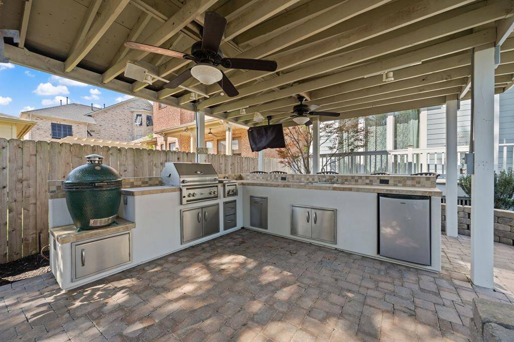 Fully equipped outdoor kitchen featuring a gas grill, sink, and mini fridge—ideal for outdoor cooking and entertaining.