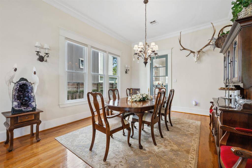 Elegant formal dining room featuring soaring ceilings and rich hardwood floors, perfect for stylish gatherings.