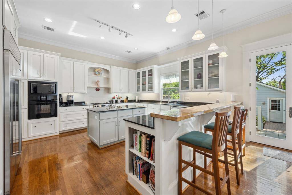 Bright and open kitchen showcasing a breakfast bar, prep island with sink, and custom cabinetry for both style and functionality.