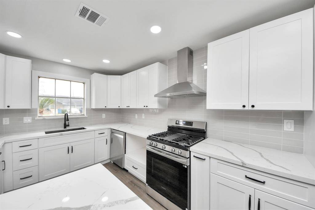 The kitchen features new cabinets with handles installed, new backsplash, new range, new dishwasher, new microwave (not pictured), new venthood, quartz countertops & a farmhouse sink with new faucets.