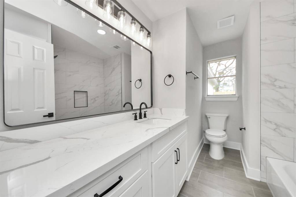A complete bathroom remodel featuring brand-new flooring, a sleek tub, a new toilet, upgraded shower fixtures, new cabinets with handles installed, Quartz countertops, a fresh sink, and all-new plumbing hardware. Plus, don’t miss those stunning framed mirrors and eye-catching light fixtures!