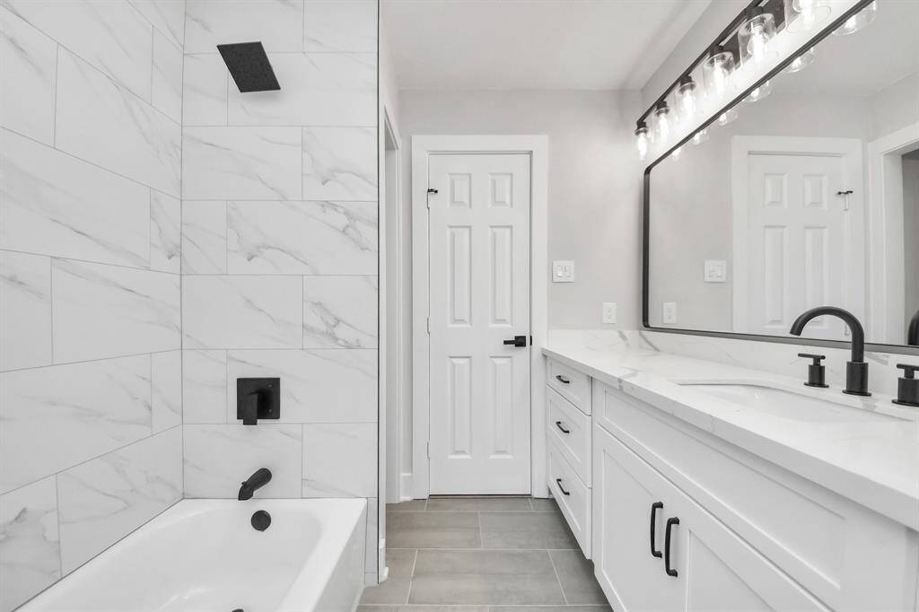 A complete bathroom remodel featuring brand-new flooring, a sleek tub, a new toilet, upgraded shower fixtures, new cabinets with handles installed, Quartz countertops, a fresh sink, and all-new plumbing hardware. Plus, don’t miss those stunning framed mirrors and eye-catching light fixtures!Shower glass door and shower base are also new. Linen closet for extra storage.